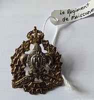 Front view of brass cap badge with identification tag