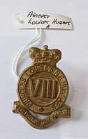 Front view of brass cap badge with tag