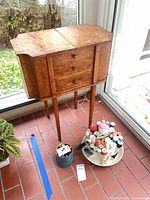 Full view of wooden sewing cabinet with notions beside