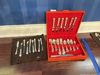 Open red case displaying assorted Birks Regency stainless flatware pieces