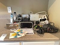 Overview showing Arlo base and cameras, Uniden phones, charging dock, Sony headphones, alarm clock