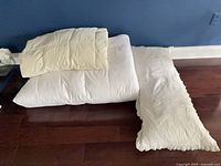 Full view of mattress topper, duvet folded on top, pillow sham beside