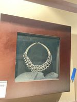 Overall view of framed necklace art in wood shadow box