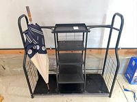 Front view of black metal golf bag organizer rack with shelves and umbrella