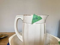 Side view of ceramic pitcher in basin showing handle and height mark