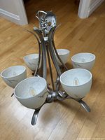 Full view of six-light grey metal chandelier with frosted glass shades