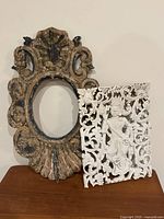 Front view of both items: distressed oval frame and whitewashed carved panel