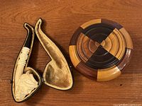 Pipe in open leather case alongside turned wood tobacco box