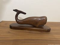 full view of wooden sperm whale on base