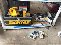Lot overview showing DeWalt toolbox with trim saw, brad nailer on box, blades and nail boxes on floor