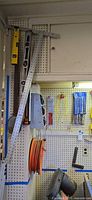 Left pegboard section with framing square, T-square, two levels, hand saw, extension cord