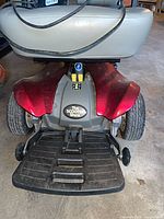 Rear view of scooter showing red body, footplate, wheels, The Scooter Store badge