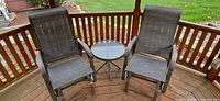 Two gray patio glider chairs and round glass-top side table on wooden deck