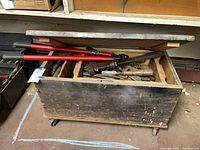 Closed wooden toolbox on casters with visible tool contents