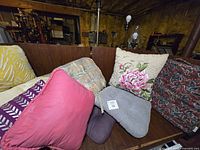 Group shot of eight assorted pillows on bench showing colours and patterns