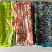 All three scarves folded side-by-side: green abstract, pink floral, teal paisley