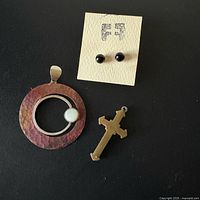 Pendant, onyx studs on card, brass cross displayed together