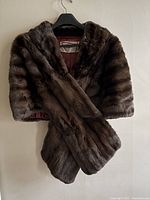 Front view of collared chestnut mink wrap hanging on hanger