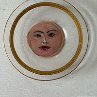 Front view of glass plate showing painted face and gold rim