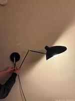 Sconce mounted, articulated arm extended, illuminated bulb