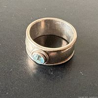 Front view of wide sterling silver band ring with bezel-set aquamarine