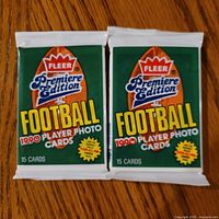 Front view of two sealed 1990 Fleer Football packs showing graphics and 15 card notation