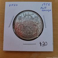 Reverse of 1950 Canadian 50 cent coin in flip showing coat of arms and date