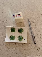 Roll of USPS Forever stamps, sheet of 4 succulent stamps, Cross mechanical pencil on countertop