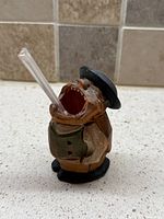 Front three-quarter view of carved wooden figure showing open mouth and hat