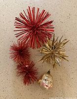Ornaments grouped: large red starburst, two small red starbursts, gold starburst, glass head