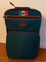 Front view of navy Lark suitcase showing pockets, leather trim, and monogram patch