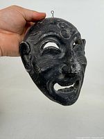 Front view of plaster mask showing facial details and hanging wire