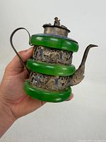 Profile view showing three green glass bands, metal spout, filigree panels