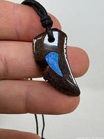 Front view of tooth-shaped pendant showing blue opal inlay and cord