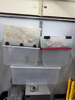 Overview showing four stacked translucent storage bins with lids, two with wheels