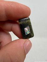 Front view of jade pendant showing silver-framed mother of pearl inlay