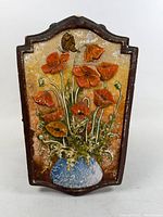 Front view of clay relief plaque showing poppies, butterfly and vase