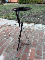 Front angle showing entire wrought iron plant stand on brick patio