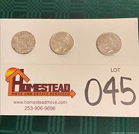 Overview of three Peace Dollars on card
