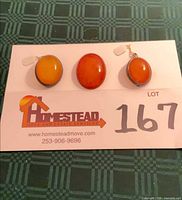 Front view of three oval amber-tone cameos on card showing relative sizes and colours
