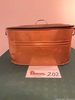Front view of oval copper boiler wash tub with lid slightly ajar showing side handles