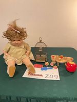 Group shot of doll, clock, miniature set, apple container and key