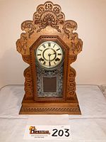 Front view showing entire carved wood case, dial, painted glass panel