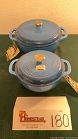 Two blue Brandani Dutch ovens with lids and tags displayed together
