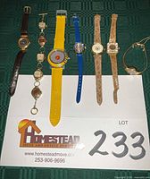 All seven wristwatches and bracelet displayed on green background