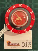 Front view of red General Electric Telechron wall clock showing dial and numerals
