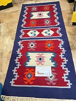 Full view of rug showing geometric pattern, fringe, size card