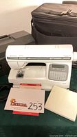 Front view of sewing machine with manual, pedal cord, accessory panel and carrying cases