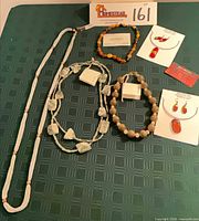 Full lot showing five necklaces, two earring sets on cards, and one bracelet-shaped amber necklace