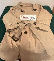 Beige double-breasted trench coat folded with belt visible